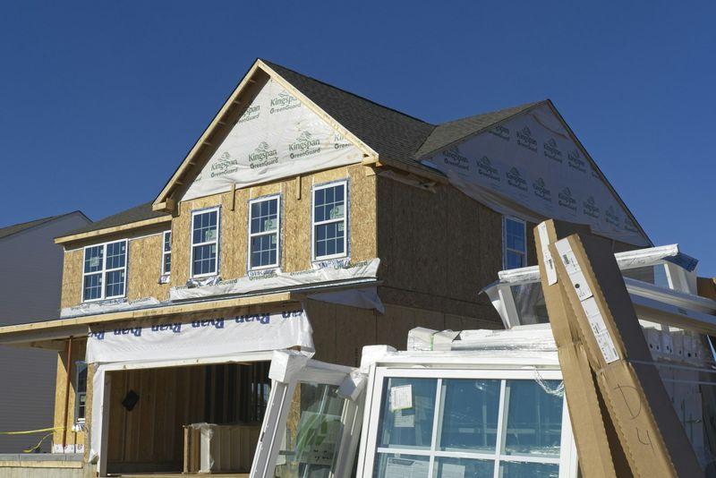 House exterior under construction with sheathing, house wrap, and new windows