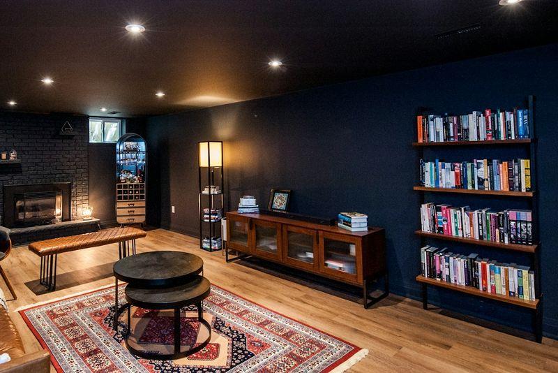 Cozy finished basement lounge with sofa, bookshelves and warm wood floors