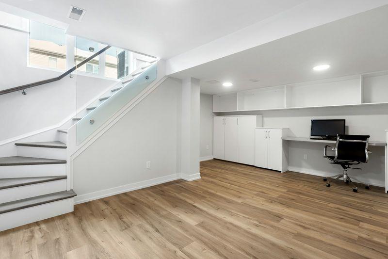 Bright finished basement office nook beside staircase with wood flooring