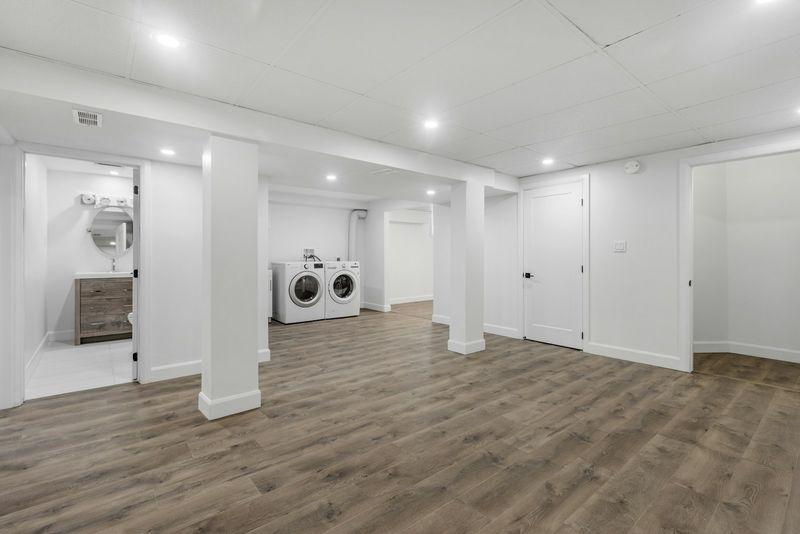 Finished basement open area with laundry zone and wood-look flooring