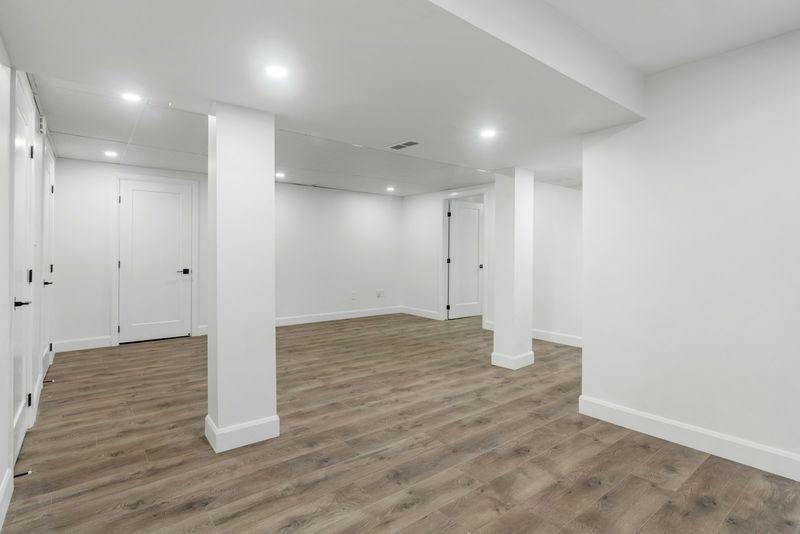 Open finished basement room with wood floors and recessed lighting