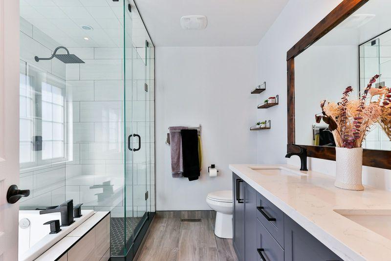 Finished bathroom with glass walk-in shower, wood-framed mirror and vanity