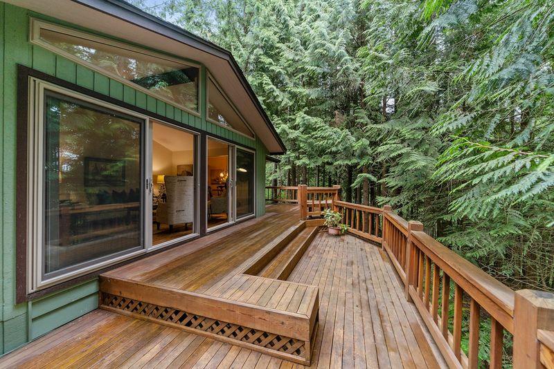 Cedar deck wrapping a green cabin with sliding glass doors