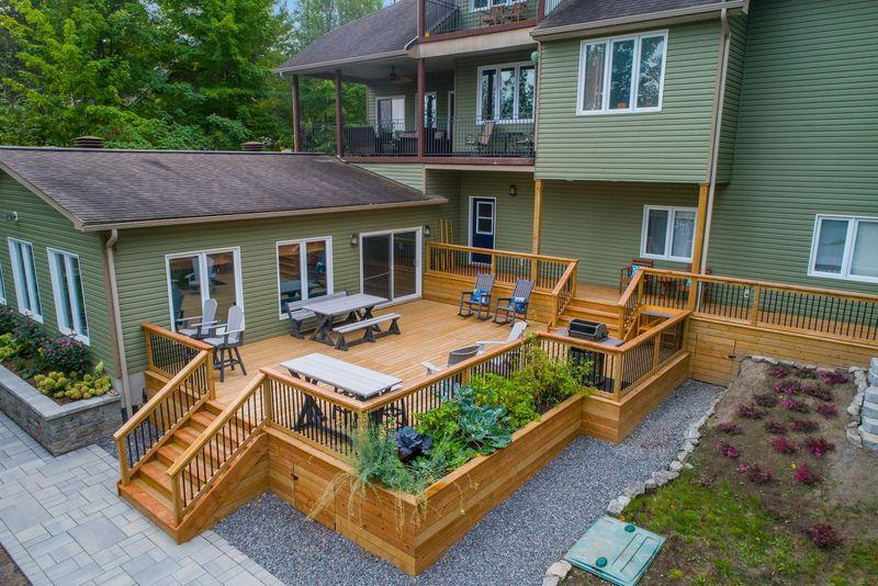 Multi-level wood deck with planter boxes behind a green house