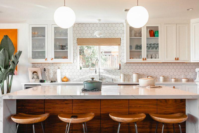 Bright kitchen with walnut island, marble counter, globe pendants and plants