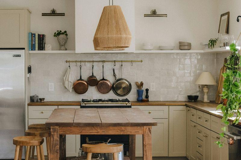 Cottage kitchen with sage cabinets, butcher block counters and rattan pendant