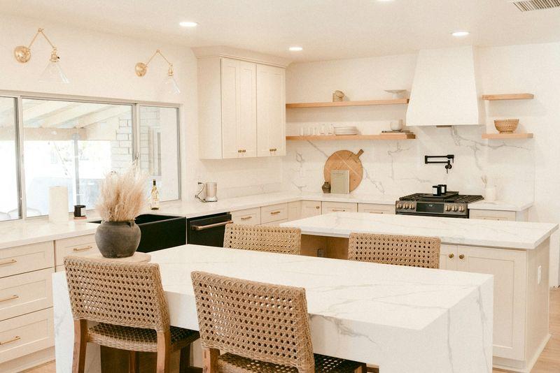 Warm white kitchen with plaster hood, oak shelves and cane island chairs