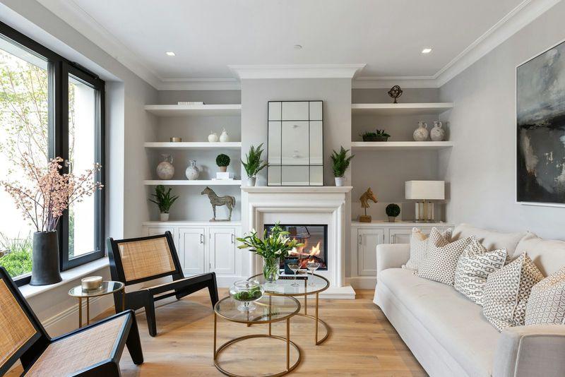 Cozy living room with built-in shelves, lit fireplace, and oak flooring